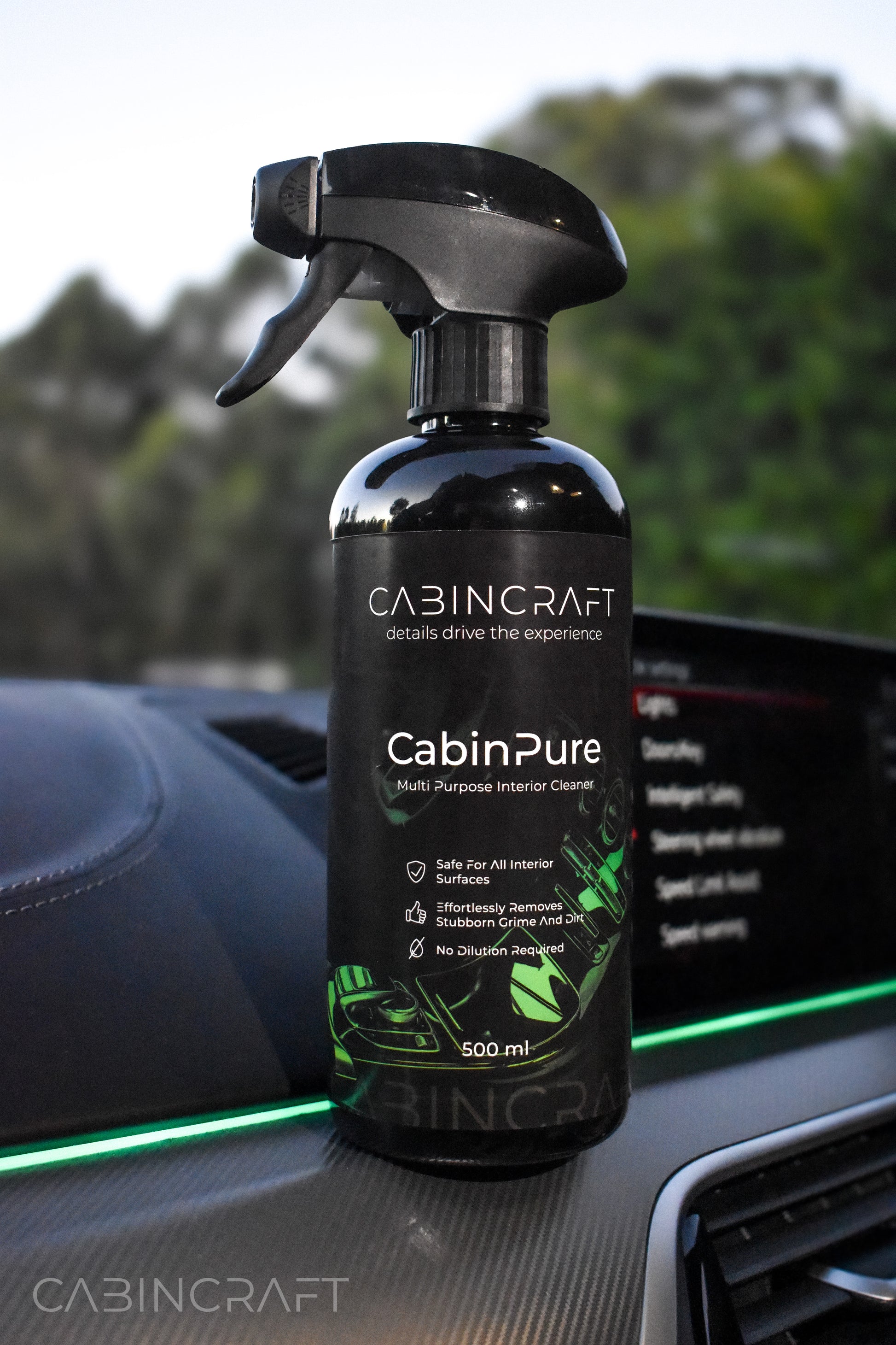 CabinPure multi-purpose interior cleaner bottle on a car dashboard with a blurred green background