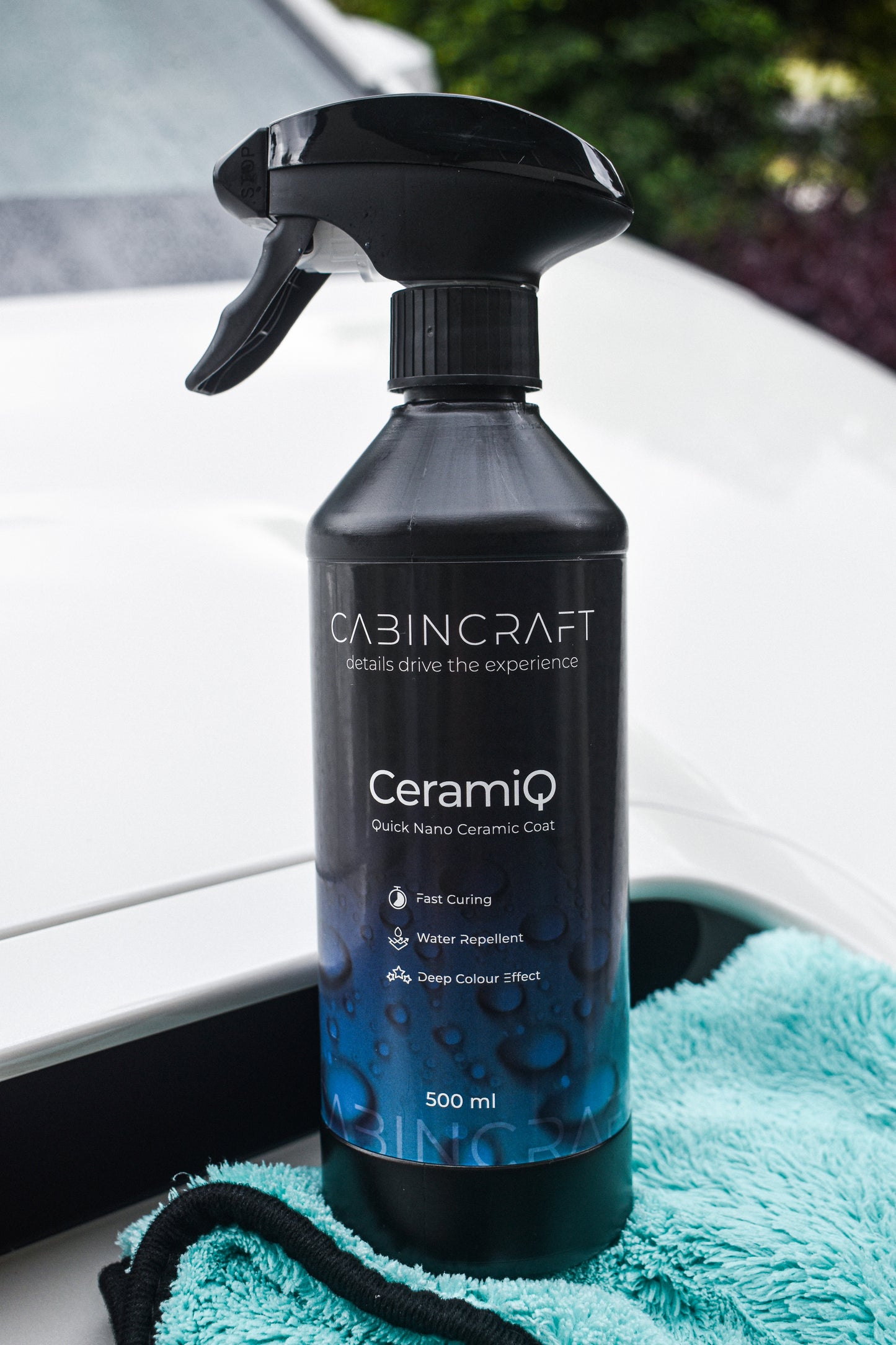 CabinCraft CeramiQ ceramic coating spray bottle on a car window with a teal towel underneath.