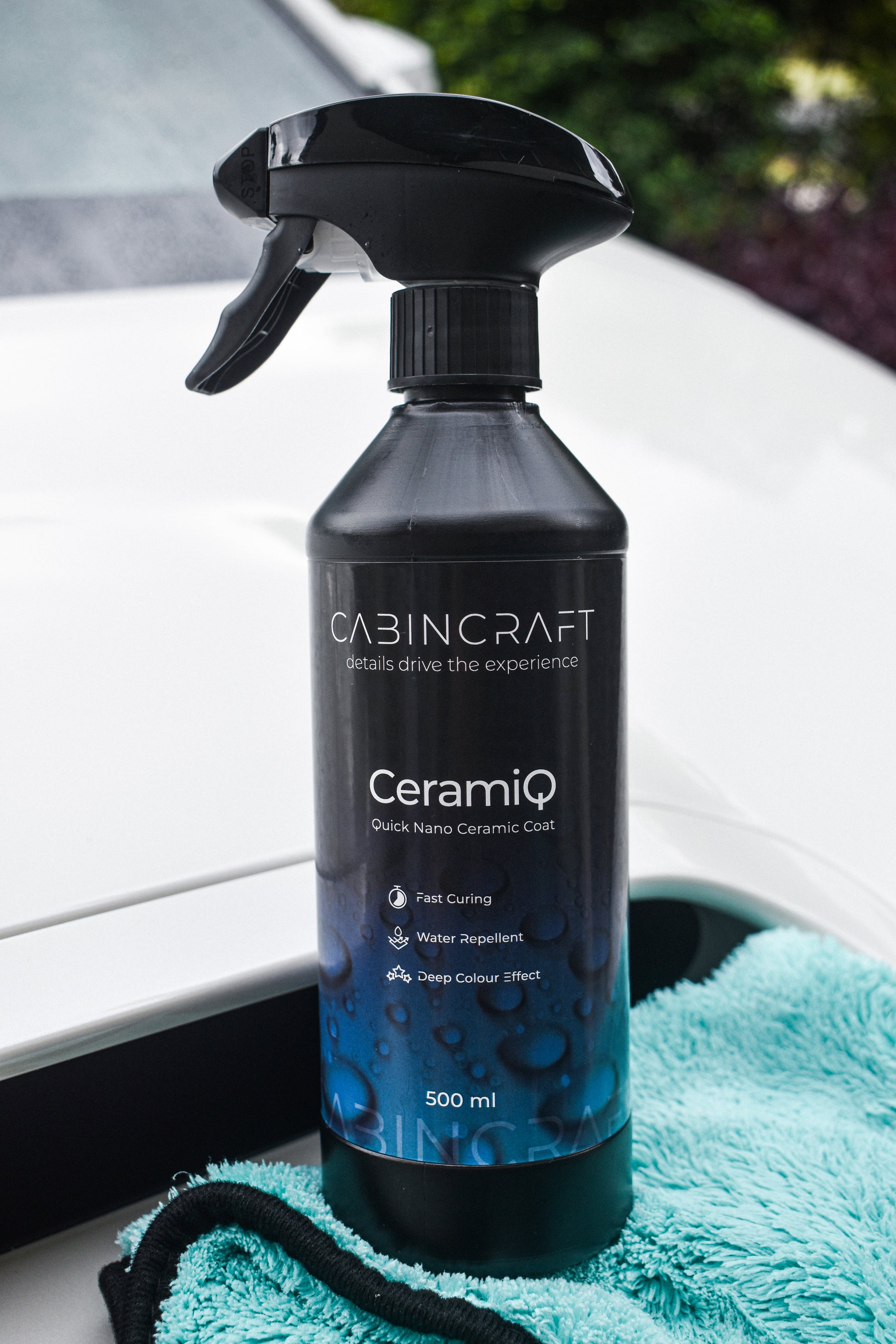CabinCraft CeramiQ ceramic coating spray bottle on a car window with a teal towel underneath.